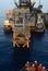 Offshore construction-workers watch as a Derrick Barge installs a RAT-soon to join upwith their platform