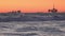 Offshore oil drilling platform and oil tanker in the ocean at sunset