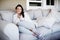 Oh so snug. Portrait of an attractive woman sitting snugly on a couch in a living room.