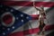 Ohio US state flag with statue of lady justice and judicial scales in dark room. Concept of judgement and punishment