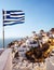 Oia, Santorini. Windmill on cliff side, and Greek flag.