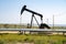 An oil derrick works in the field on a sunny day. California is one of the United States