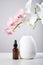 Oil diffuser with glass amber bottle and orchid flowers on white table