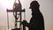 Oil drill, field pump jack silhouette with setting sun and worker. Oil field, the oil workers are working.