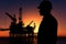 Oil Drill, field pump jack silhouette with setting sun and worker.Refinery, natural gas. Lens Flare. Generative AI
