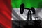 Oil drilling pump on background of flag of Emirates