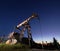 Oil field with petroleum pump jack under beautiful night sky.