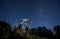 Oil field with petroleum pump jack under night starry sky.