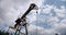 Oil Field Pump Jack Against Blue Sky and clouds. Slow motion Wide shot view