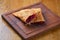 Oil fried crunchy pie. Fruit closed pie cut in half. Cherry hot pocket pie served on a wooden board.