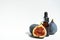 Oil in a glass bottle with a pipette. A bottle of fig oil with fresh fruit on a white background. Organic natural bio-oil.