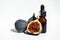 Oil in a glass bottle with a pipette. A bottle of fig oil with fresh fruit on a white background. Organic natural bio-oil.