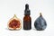 Oil in a glass bottle with a pipette. A bottle of fig oil with fresh fruit on a white background. Organic natural bio-oil.