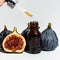 Oil in a glass bottle with a pipette. A bottle of fig oil with fresh fruit on a white background. Organic natural bio-oil.