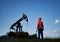 Oil man standing near petroleum pump jack in oil field.