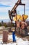 Oil man working in oil field with petroleum pump jack.