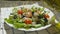 Oil pouring into bowl of greek salad