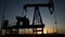 oil production. silhouette oil and gas production rig at sunset glare. oilfield lifestyle business a extraction concept