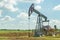 Oil pump in the field, beautiful blue sky with clouds. Russian oil production