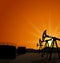 Oil pump jack for petroleum and reserve tanks on sunrise background