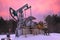 Oil pump jack winter working. At the orange sunset dawn of the sky with clouds. Oil rig energy industrial machine for petroleum in