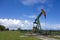 Oil pump jack in work. Oil industry in Seria, Brunei Darussalam on a sunny day with cloudy blue skies