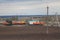 Oil pumpjack and fuel trucks among grassy field at sunny day