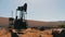 Oil pumpjacks in a working oil field in Baku, Azerbaijan.Silhouette of working oil pump and an old rusty iron barrel