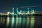 Oil refinery at night with light from boat