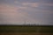 Oil refinery seen on the horizon on the wheat field at sunset