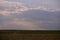 Oil refinery seen on the horizon on the wheat field at sunset