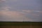 Oil refinery seen on the horizon on the wheat field at sunset