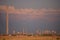Oil refinery seen on the horizon on the wheat field at sunset