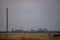 Oil refinery seen on the horizon on the wheat field at sunset. Polluting industry in the environment