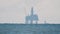 Oil water platform silhouette on horizon in hazy air over sea surface