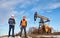 Oil workers standing on territory of oil field with pump jack.