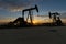 Oilfield pump jacks silhouetted against a morning sunrise