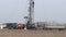 Oilfield with workers and drilling rig