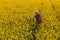 Oilseed rape farmer examining crop flowers in field