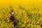 Oilseed rape farmer examining crop flowers in field