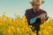 Oilseed rape farmer using tablet computer in blooming field