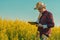 Oilseed rape farmer using tablet computer in blooming field