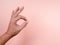 OK, hand sign gesture by man adult  on pastel pink background.