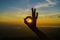 Ok sign silhouette on beautiful sunset above the mountain in the form of Woman okay shaped hand gesture