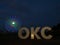 OKC Sign at Night with the Fully Lit Wheeler Ferris Wheel in the Background in Oklahoma City