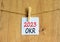 OKR objectives and key results symbol. White paper with words OKR 2023 clip on wooden clothespin. Beautiful wooden background.