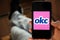 OKS logo on the screen of mobile phone in mans hand. Application for dating and acquaintance. Man is laying on the sofa