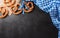 Oktoberfest festival decoration symbols made from Pretzel loaf and Bavarian white and blue fabric on dark stone background