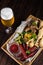 Oktoberfest food snacks concept top view. Wooden table with a glass of cold beer with water droplets and a big wooden box with