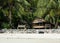 Old Abandon Wooden Fisherman Cabin with Wooden Bench under Palm Trees on The Island